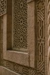Close-up of a historic building's ornate stone facade featuring intricate geometric patterns and arches.